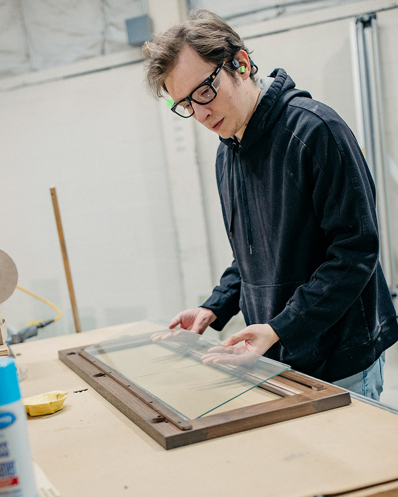 A QCCI team member fits glass onto a cabinet door